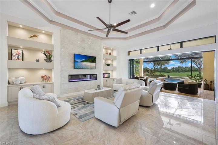 Note the custom built-in cabinets with decorative tile and fireplace, tile flooring, and indoor-outdoor living space.