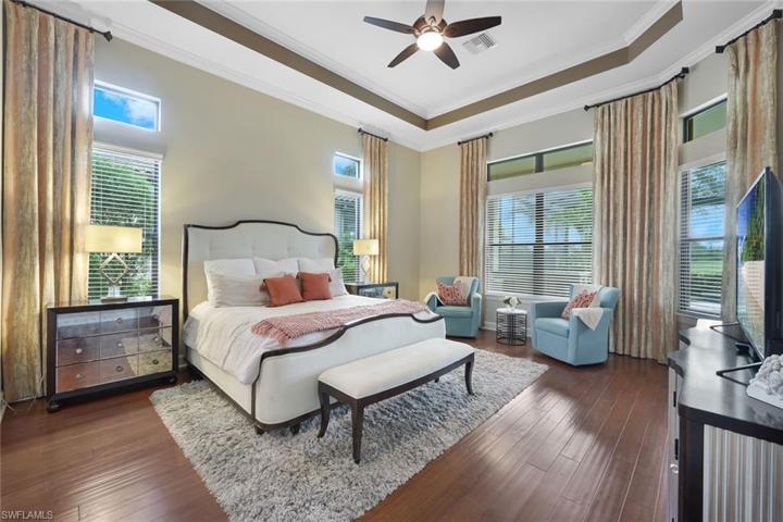Relax in your owner's suite, with tray ceilings, crown molding, engineered hardwood floors, a view of the pool, and plenty of light.