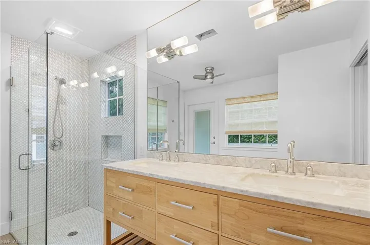 Full bath with double vanity, a shower, and ceiling fan