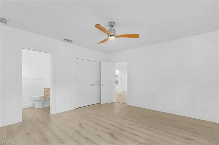 Bedroom with light wood-style flooring, ensuite bath, a closet, and ceiling fan