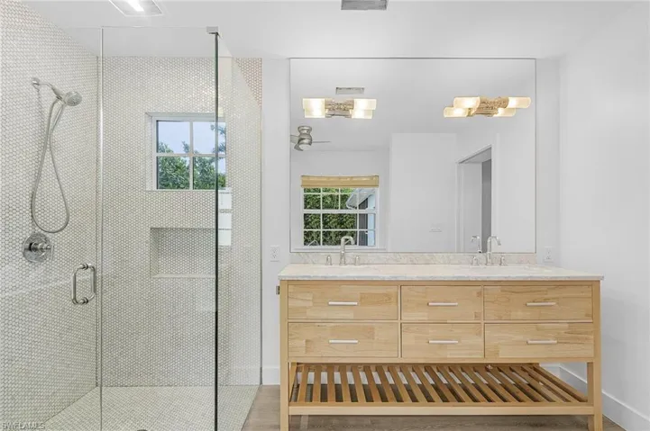 Bathroom with double vanity and a shower, and an exterior door leading to pool