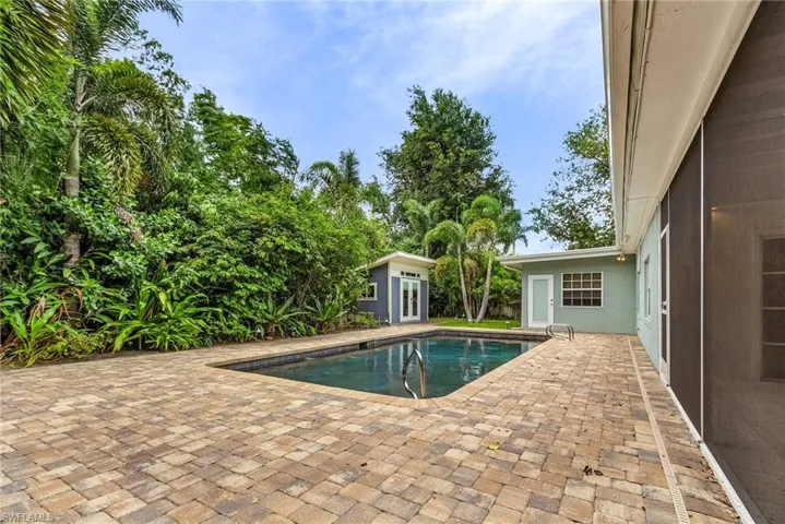 Outdoor pool featuring a detached office and a patio area