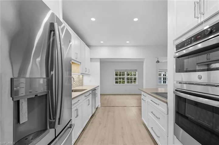 Kitchen featuring appliances with stainless steel finishes, light wood finished floors, white cabinets, decorative backsplash, and recessed lighting