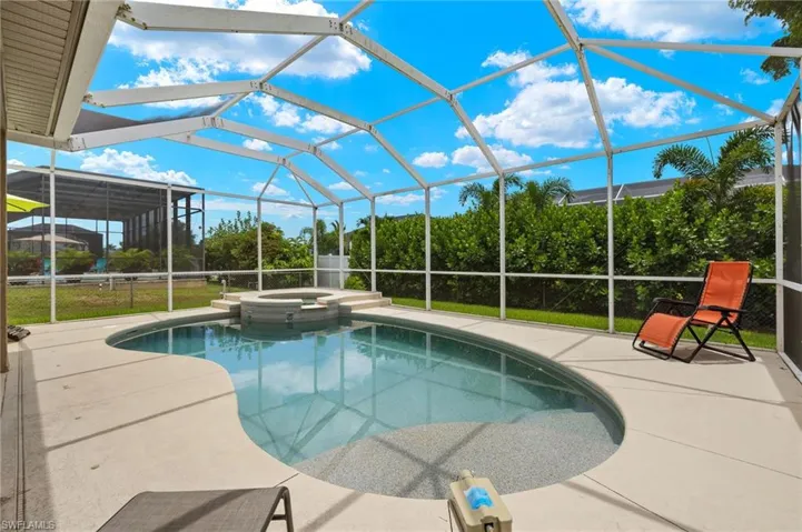 View of swimming pool with a patio area, an in ground hot tub, and glass enclosure