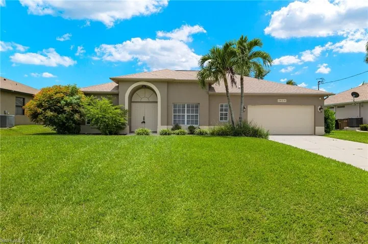 View of front of property with a garage, a front lawn, and cooling unit