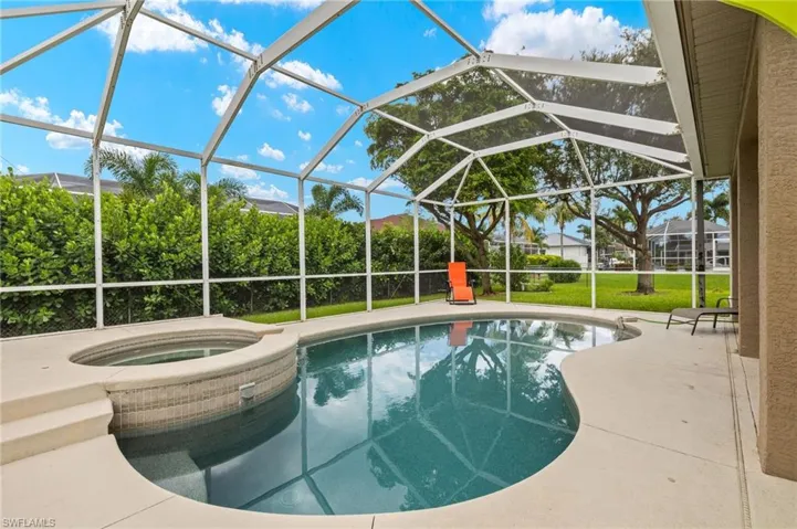 View of pool featuring an in ground hot tub, a patio, and glass enclosure
