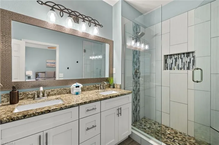 Bathroom featuring a shower with shower door and double vanity