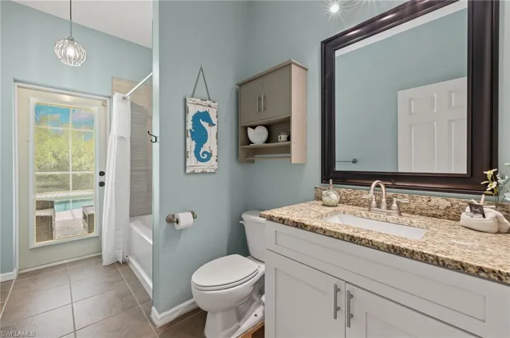 Full bathroom featuring toilet, tile patterned floors, shower / bathtub combination with curtain, and vanity