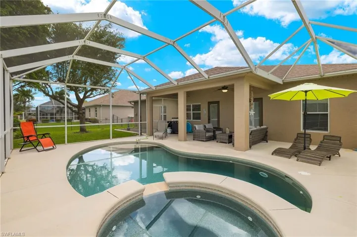 View of swimming pool with a patio, an in ground hot tub, a lanai, a yard, and an outdoor living space