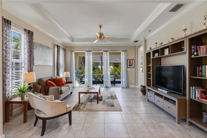 Living area featuring a ceiling fan, a tray ceiling, and crown molding