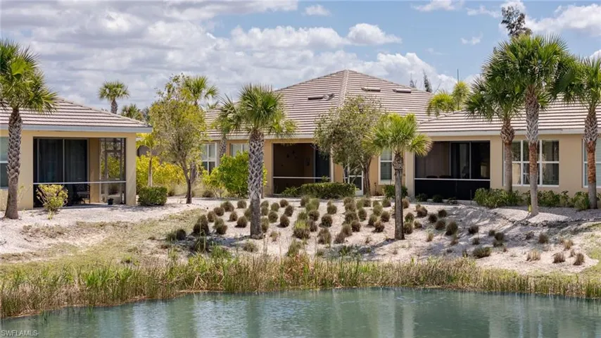 Rear view of house featuring a sunroom, a tiled roof, stucco siding, and a water view