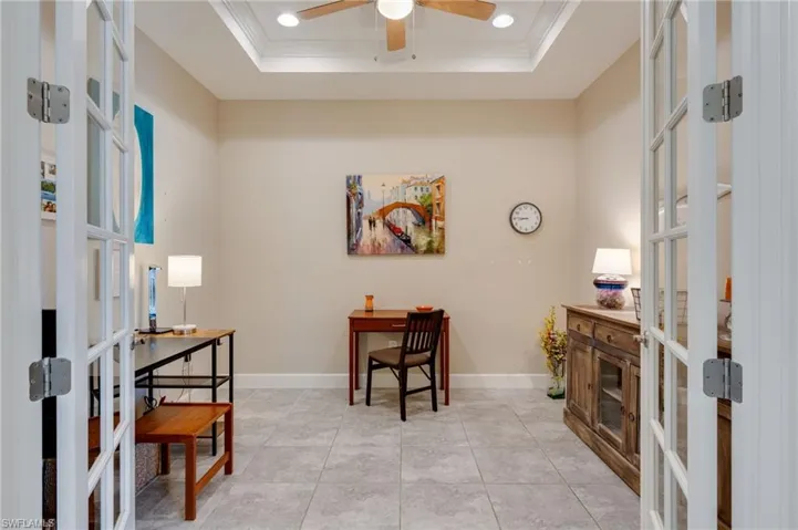 Office space with french doors, ornamental molding, ceiling fan, a raised ceiling, and light tile patterned floors