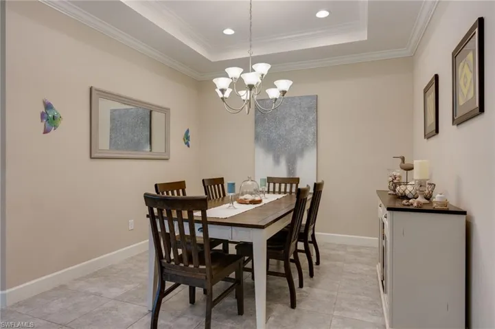 Dining area with crown molding, suspended lighting, a raised ceiling, and light tile patterned flooring
