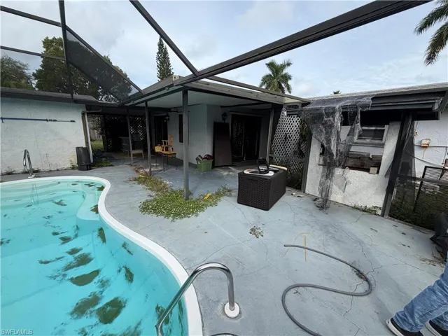 Screened-in patio area featuring a concrete deck and an in-ground swimming pool with metal handrails