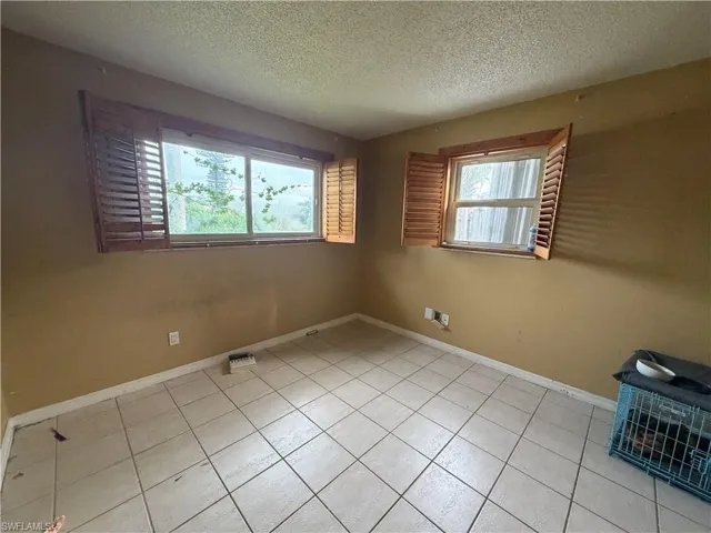 Interior space featuring ceramic tile flooring, two multi-pane windows, and attached wooden shutters
