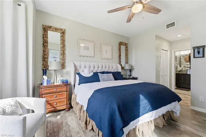 Bedroom featuring ensuite bathroom, wood finished floors, a ceiling fan, and a closet