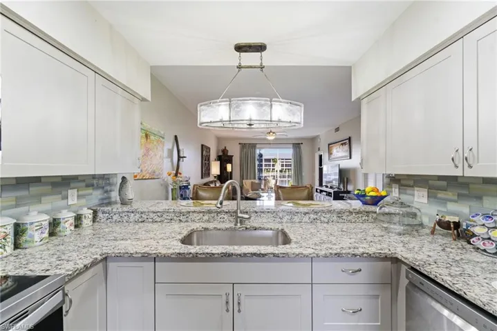 Kitchen with tasteful backsplash, light stone counters, and stainless steel appliances