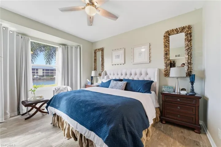 Bedroom featuring a water view, wood finished floors, and a ceiling fan