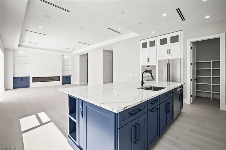 Kitchen with a tray ceiling, white cabinets, open floor plan, appliances with stainless steel finishes, and recessed lighting