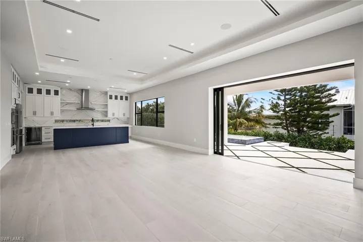 Unfurnished living room with recessed lighting, a raised ceiling, light wood-style floors, and wine cooler