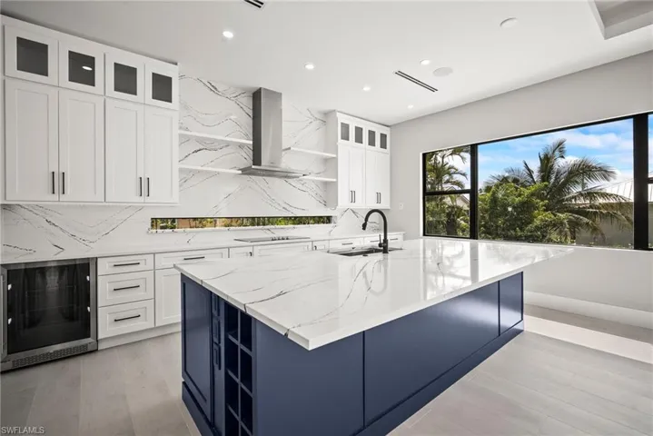 Kitchen with open shelves, decorative backsplash, glass insert cabinets, white cabinets, and beverage cooler