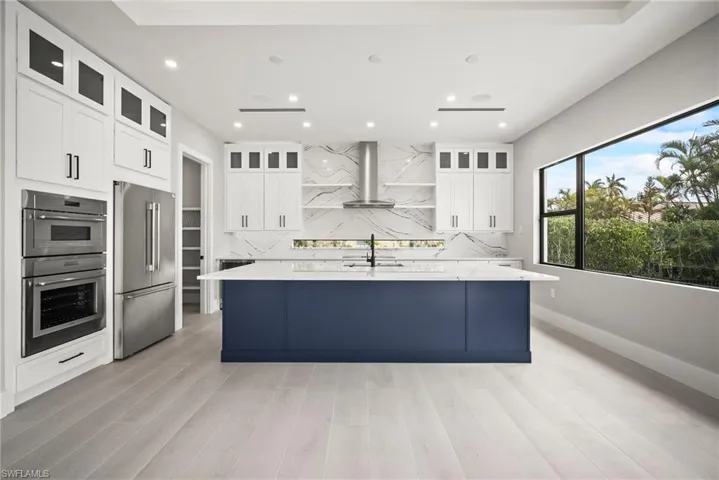 Kitchen with backsplash, white cabinets, a large island, and recessed lighting