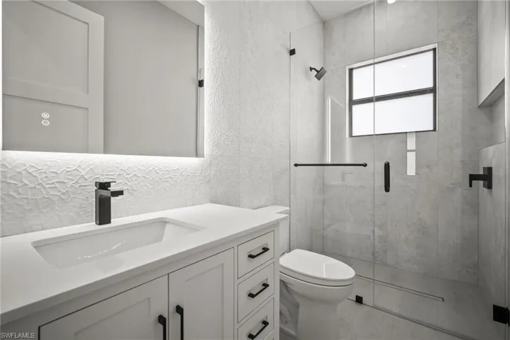 Full bath featuring vanity, a shower stall, and a textured wall