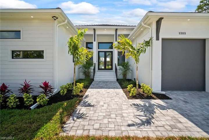 Entrance to property featuring an attached garage, french doors, and stucco siding
