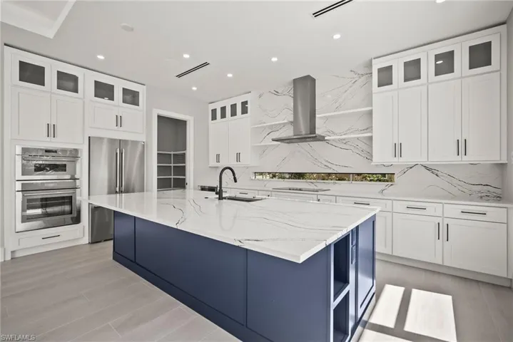 Kitchen with glass insert cabinets, open shelves, tasteful backsplash, white cabinets, and appliances with stainless steel finishes