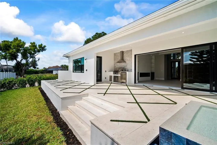 Rear view of house with exterior kitchen, stucco siding, a patio area, and a lawn