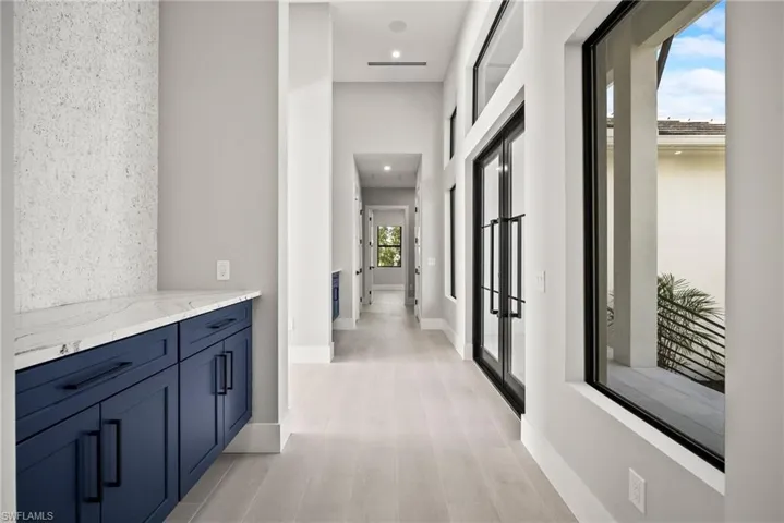 Hallway featuring light wood-type flooring, recessed lighting, and a high ceiling