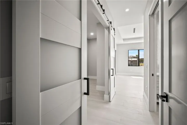 Hall featuring a barn door, light wood-type flooring, and recessed lighting