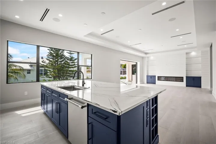 Kitchen featuring a tray ceiling, light wood-style floors, light stone counters, open floor plan, and recessed lighting