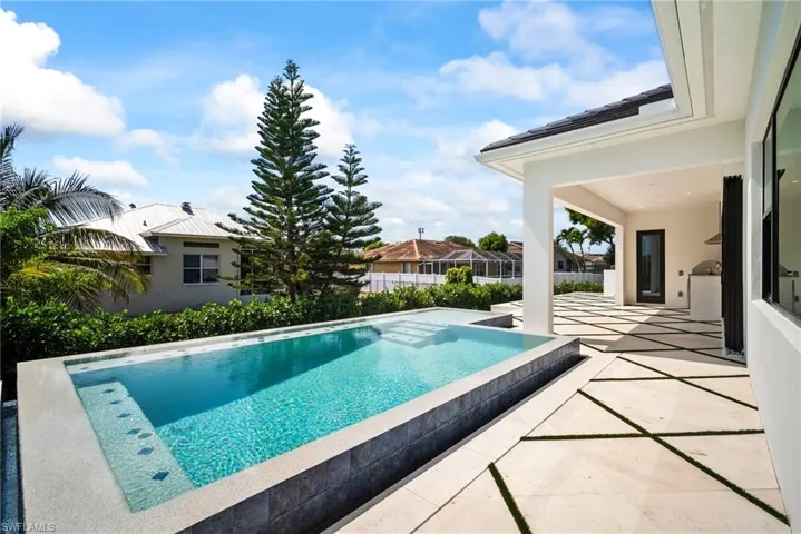 View of swimming pool with a patio, an infinity pool, and a hot tub