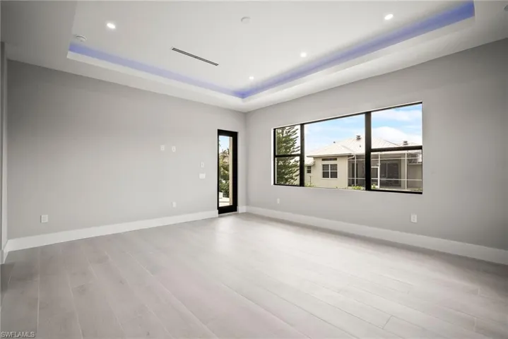 Spare room with a tray ceiling, light wood finished floors, and recessed lighting