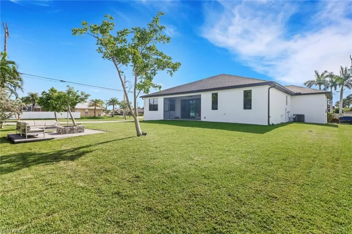 Back of house with a lawn, stucco siding, and roof with shingles
