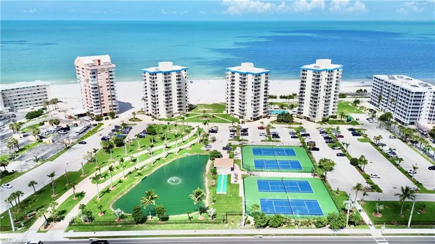 Three buildings with blue stripe at top and the grounds ,tennis , pickleball ,pond and more