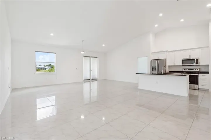 Unfurnished living room with high vaulted ceiling