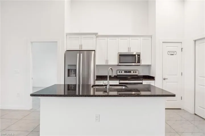 Kitchen with a center island with sink, white cabinets, and stainless steel appliances