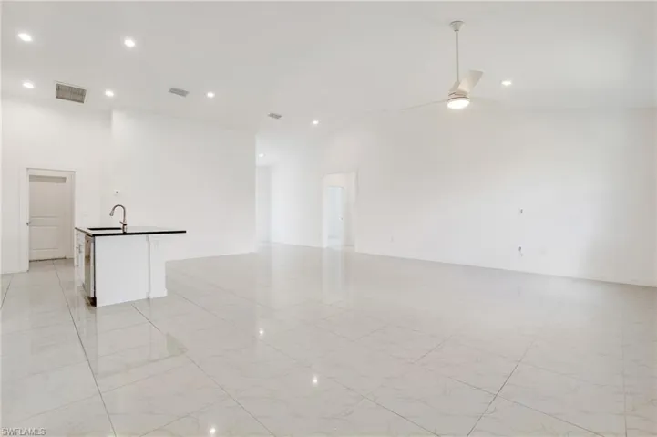 Empty room with sink, high vaulted ceiling, and ceiling fan