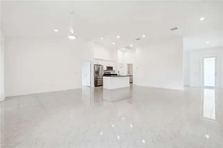 Unfurnished living room with ceiling fan and high vaulted ceiling
