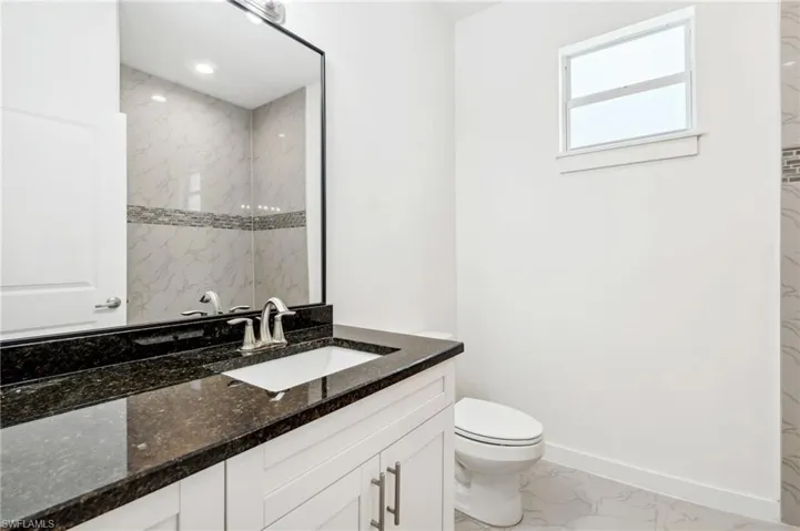 Bathroom featuring vanity, tiled shower, and toilet