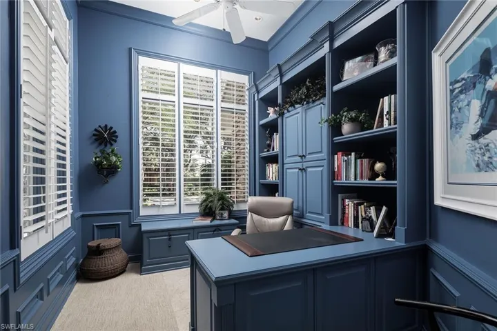 Office space featuring a decorative wall, wainscoting, a ceiling fan, and ornamental molding