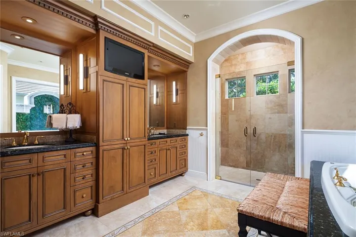 Bathroom with a stall shower, crown molding, a wainscoted wall, vanity, and a garden tub