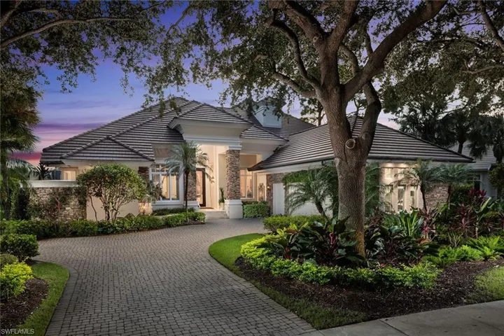 View of front of home featuring a tile roof, stone siding, decorative driveway, stucco siding, and an attached garage