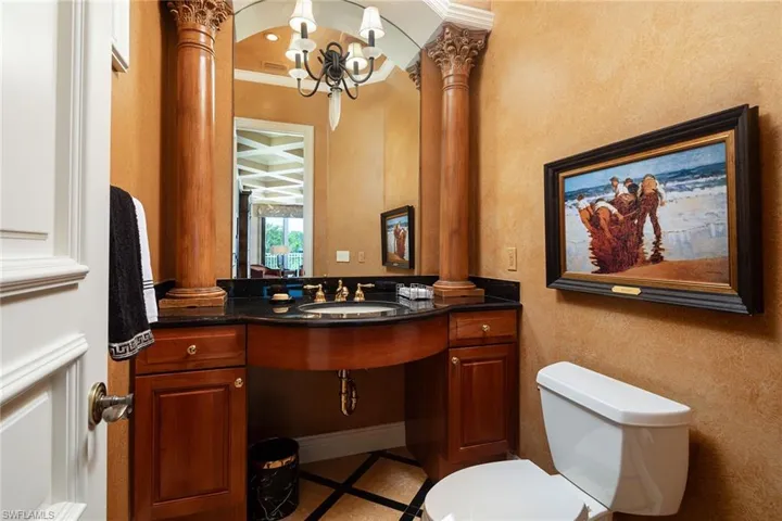 Bathroom featuring inlaid floor details, vanity, decorative columns, ornamental molding, and hanging lights