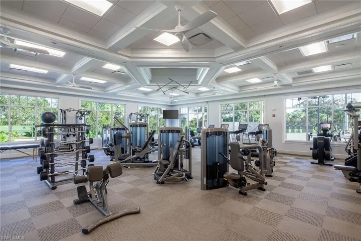 Exercise room with coffered ceiling, ceiling fan, and crown molding