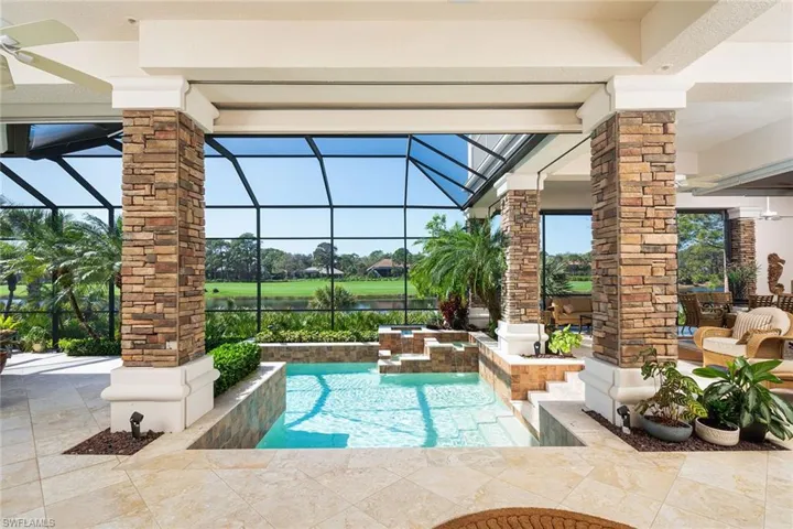 Integrated pool / hot tub featuring glass enclosure, a water view, and a patio