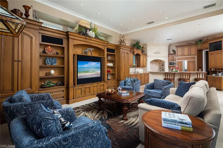 Living room with built in shelves, recessed lighting, and ornamental molding