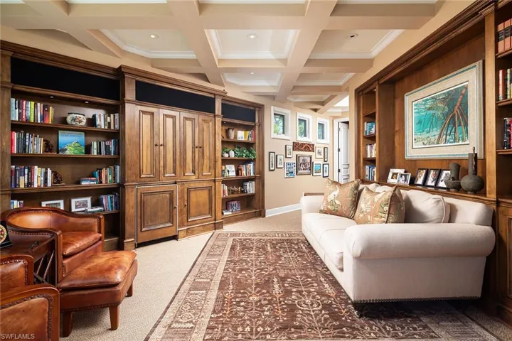 Sitting room featuring light colored carpet, built in shelves, coffered ceiling, and recessed lighting